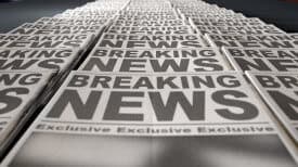 A long row of folded newspapers at the end of a press run with a generic headline that reads breaking news on the front page on an isolated white background