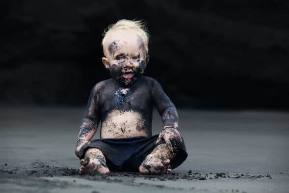 Portrait Of Dirty Child On The Black San Beach